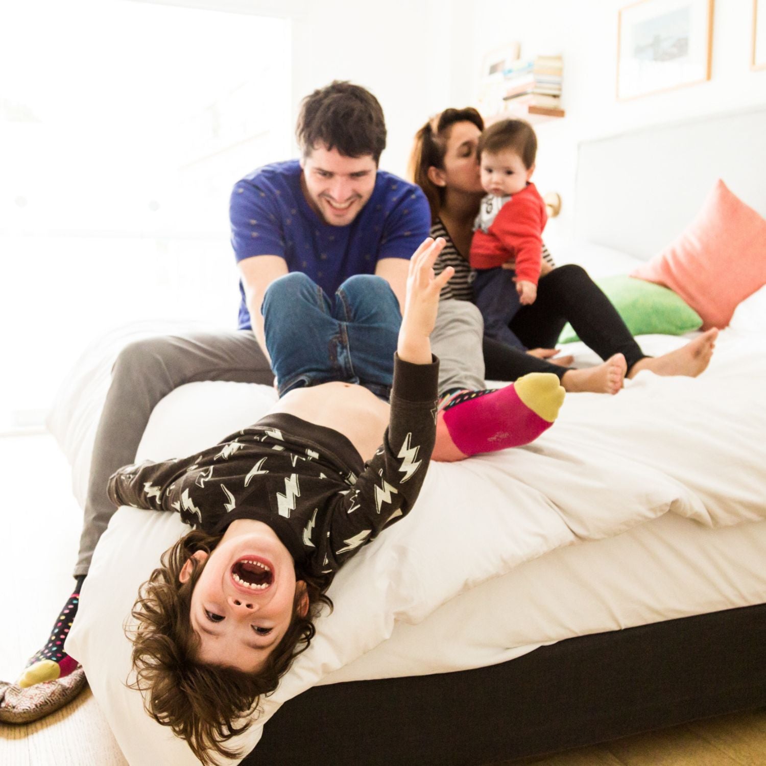 Familia compuesta por dos padres y dos niños sobre una cama.